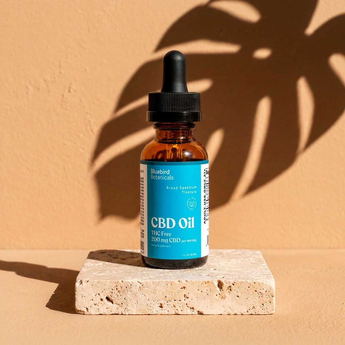 CBD oil dropper bottle on a beige surface with a brown background
