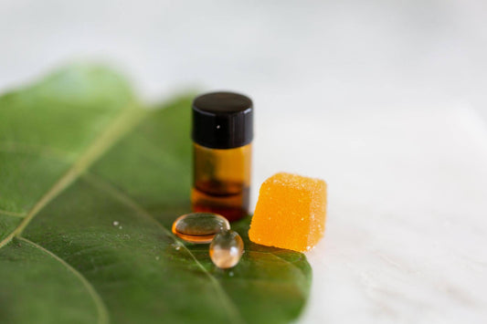 cbd gummy next to an oil tincture bottle on a leaf-designed counter