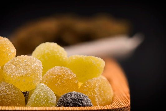 Yellow gummies isolated on in a wooden bowl against a dark backdrop