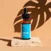 CBD oil dropper bottle on a beige surface with a brown background