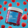 A jar of Bluebird Botanicals Lift Tropical Punch Delta THC Gummies floating against a bright blue background with floating red gummy candies. The jar has a white screw cap and a label that is blue on top and magenta/pink on the bottom, with the product name 'Lift Delta THC Gummies' clearly visible.; Flavor: Tropical Punch;