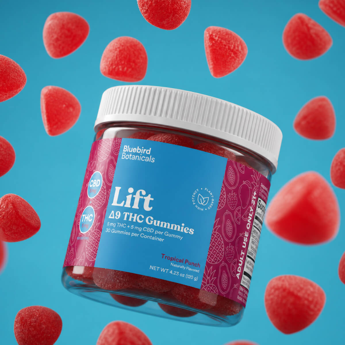 A jar of Bluebird Botanicals Lift Tropical Punch Delta THC Gummies floating against a bright blue background with floating red gummy candies. The jar has a white screw cap and a label that is blue on top and magenta/pink on the bottom, with the product name 'Lift Delta THC Gummies' clearly visible.; Flavor: Tropical Punch;