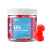 A clear plastic jar of Bluebird Botanicals Lift Tropical Punch Delta THC Gummies with a white ribbed lid and a blue and magenta label, shown alongside three red gummy candies on a white background.; Flavor: Tropical Punch;