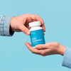 Two hands holding a bottle of Bluebird CBD Gummies on a blue background.; Strength: 100 mg;
