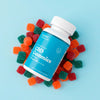 Bottle of Bluebird CBD gummies laying on a pile of gummies on a blue background.; Strength: 50 mg;