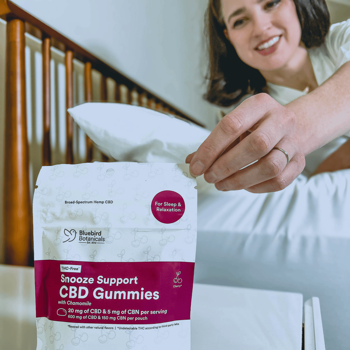 Person holding a package of Snooze Support CBD Gummies with Bluebird Botanicals branding.