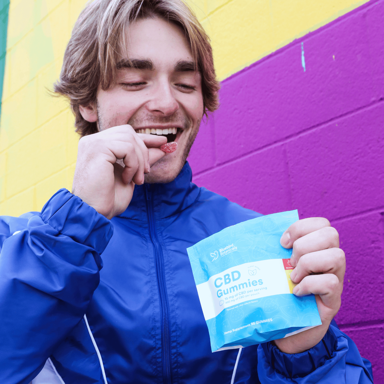 Person holding a package of CBD Gummies against a colorful background